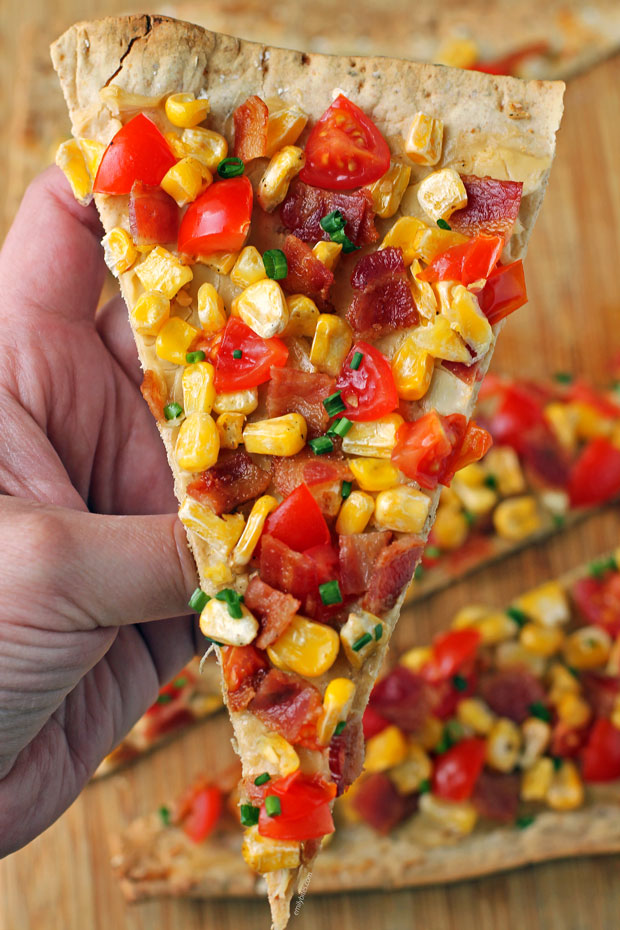 Bacon, Corn and Tomato Flatbread slice in hand