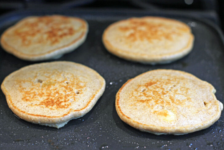 Peach Oatmeal Pancakes cooking on griddle pan