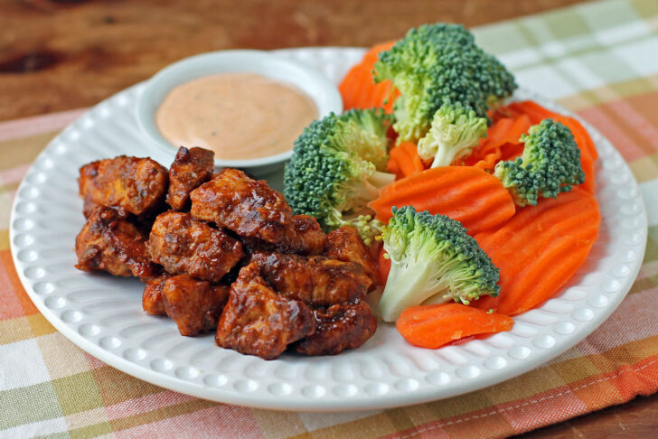 Saucy Barbecue Chicken Bites on a plate with veggies and dip